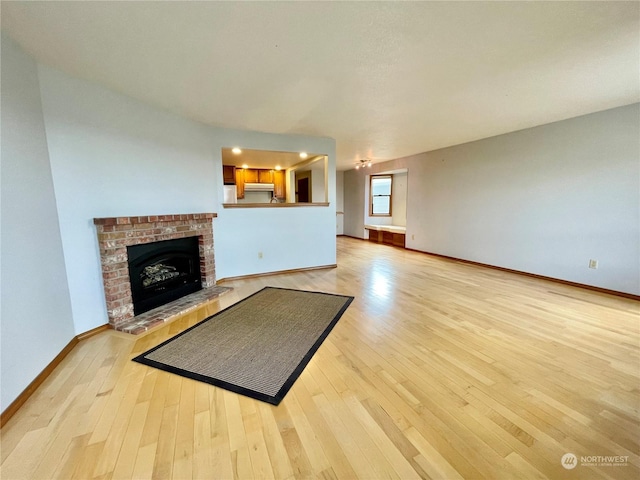 living room with a brick fireplace and light wood-type flooring