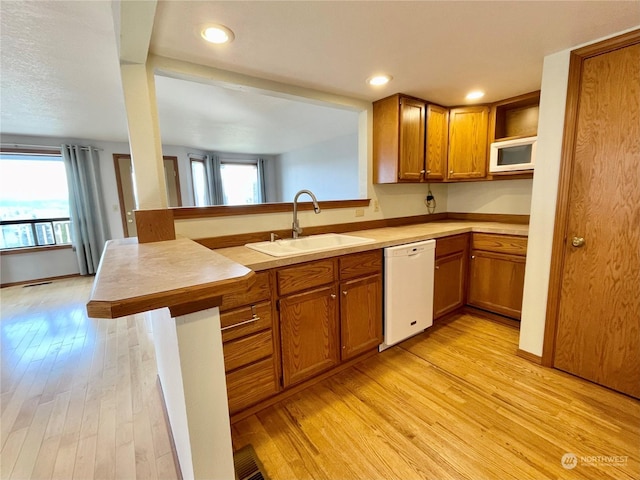 kitchen featuring sink, light hardwood / wood-style floors, kitchen peninsula, and white appliances