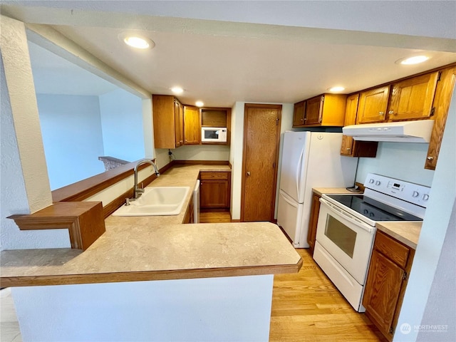 kitchen with kitchen peninsula, sink, white appliances, and light hardwood / wood-style flooring