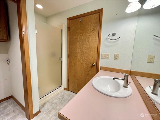 bathroom featuring a shower with door and vanity