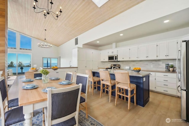 dining area with high vaulted ceiling, wood ceiling, light hardwood / wood-style floors, a water view, and an inviting chandelier