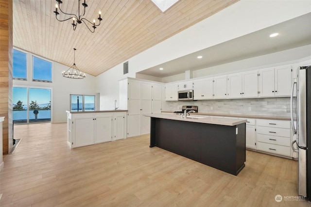 kitchen featuring a kitchen island with sink, white cabinetry, stainless steel appliances, a notable chandelier, and decorative light fixtures