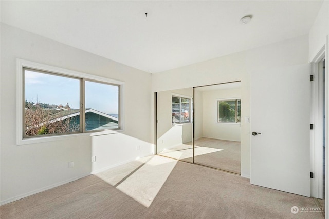 unfurnished bedroom with light carpet and a closet