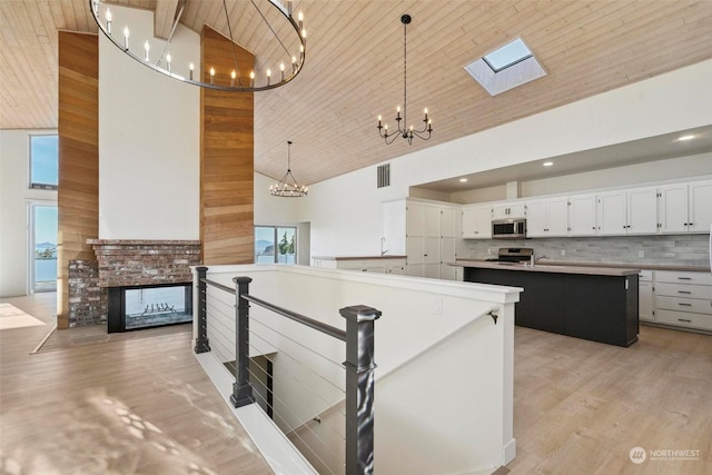 kitchen featuring white cabinetry, a center island, wooden ceiling, pendant lighting, and stainless steel appliances