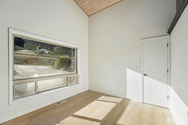 empty room with vaulted ceiling, wood ceiling, and light hardwood / wood-style floors