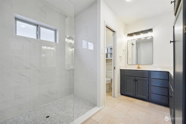 bathroom featuring vanity, a tile shower, and toilet