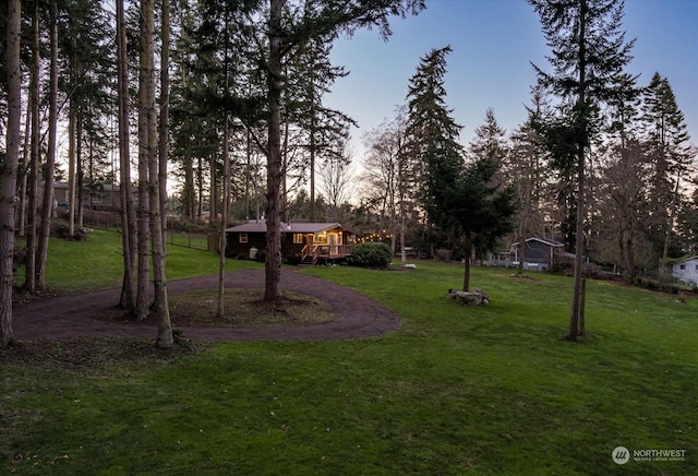 yard at dusk featuring a wooden deck