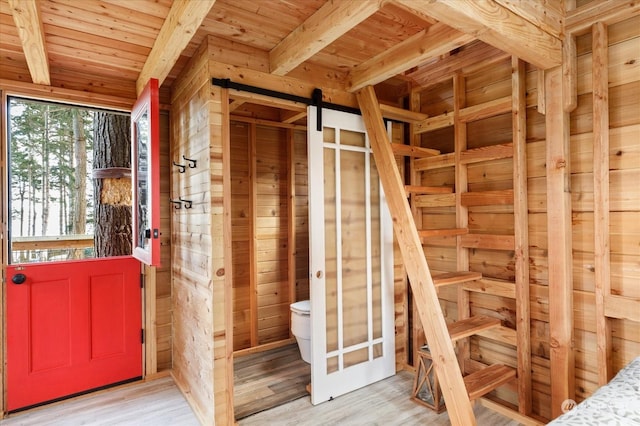 miscellaneous room featuring light wood-type flooring, beamed ceiling, a barn door, and wooden ceiling