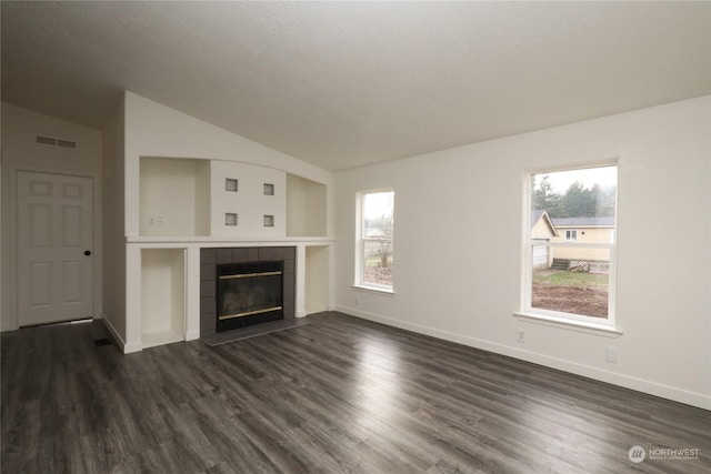 unfurnished living room featuring dark wood-type flooring, lofted ceiling, and a tile fireplace