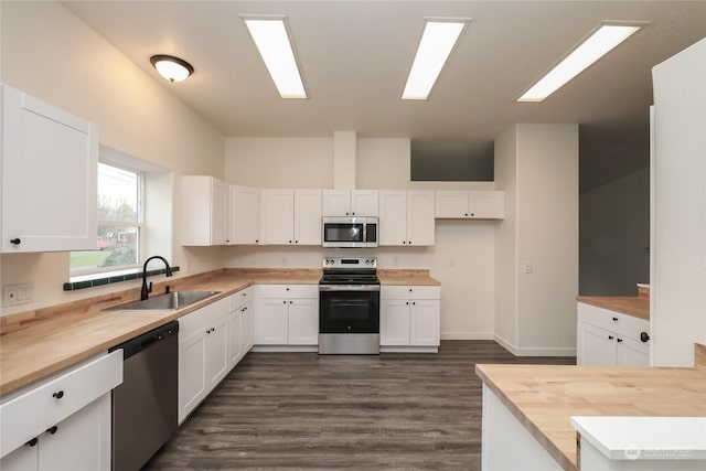 kitchen with stainless steel appliances, butcher block counters, white cabinets, and sink