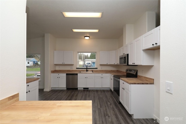 kitchen with butcher block countertops, appliances with stainless steel finishes, dark hardwood / wood-style flooring, white cabinets, and sink