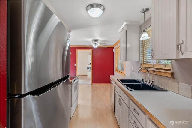 kitchen featuring sink, white cabinets, hanging light fixtures, ornamental molding, and stainless steel appliances