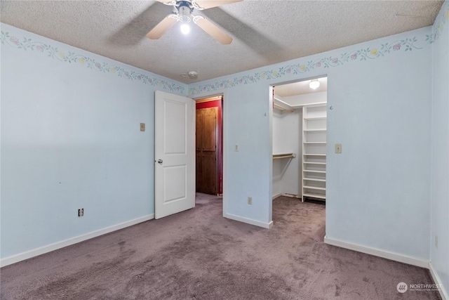 unfurnished bedroom with a spacious closet, light colored carpet, a textured ceiling, and ceiling fan