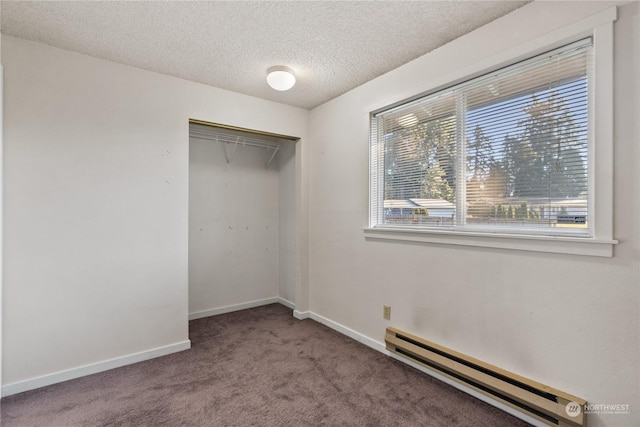 unfurnished bedroom with a baseboard heating unit, a closet, a textured ceiling, and carpet flooring