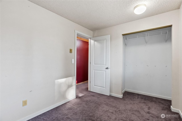 unfurnished bedroom with dark colored carpet, a textured ceiling, and a closet