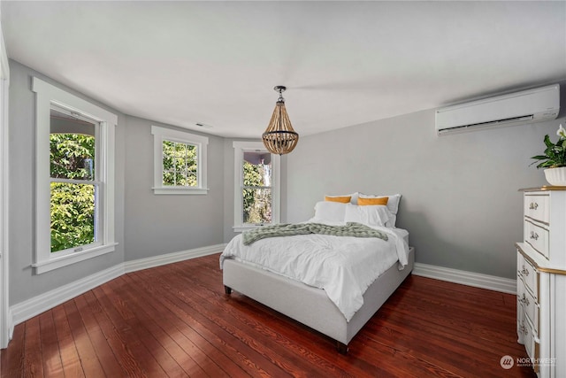 bedroom with an inviting chandelier, an AC wall unit, and dark hardwood / wood-style flooring