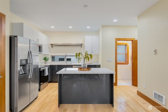 kitchen featuring sink, white cabinets, a center island, light hardwood / wood-style floors, and stainless steel appliances