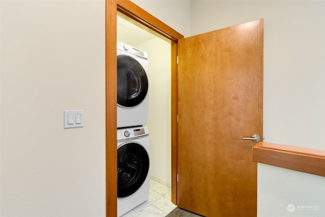 laundry area with light tile patterned floors and stacked washer and dryer