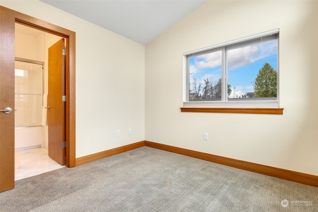 carpeted empty room featuring vaulted ceiling