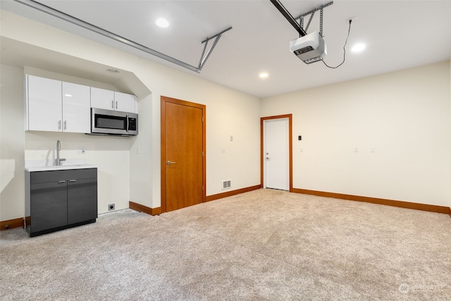 kitchen featuring light carpet, white cabinets, and sink