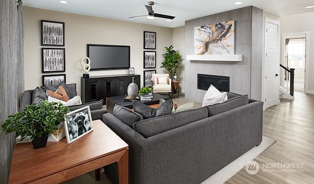 living room with ceiling fan, light hardwood / wood-style floors, and a fireplace