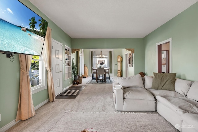 living room featuring a notable chandelier, a wealth of natural light, and light colored carpet