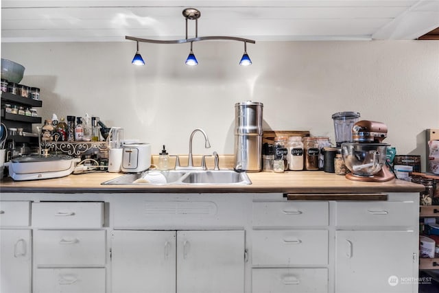 kitchen with sink, hanging light fixtures, and white cabinets