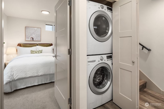 laundry room with stacked washer and clothes dryer and hardwood / wood-style floors