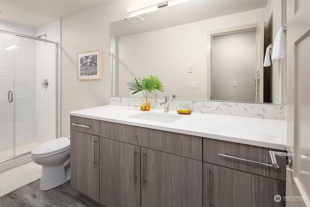 bathroom with toilet, vanity, a shower with shower door, and hardwood / wood-style flooring