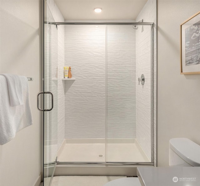 bathroom featuring a shower with shower door and toilet