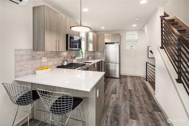 kitchen featuring kitchen peninsula, appliances with stainless steel finishes, pendant lighting, a breakfast bar, and sink