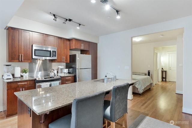 kitchen with a breakfast bar area, stainless steel appliances, a kitchen island with sink, and sink