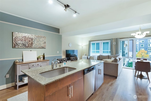 kitchen featuring decorative light fixtures, sink, a kitchen island with sink, light wood-type flooring, and stainless steel dishwasher