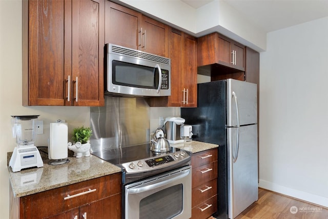 kitchen featuring light stone countertops, stainless steel appliances, and light hardwood / wood-style flooring