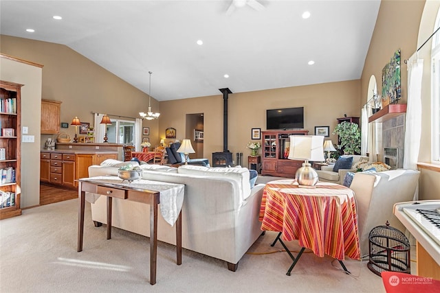 living room featuring vaulted ceiling, light carpet, a wood stove, and an inviting chandelier