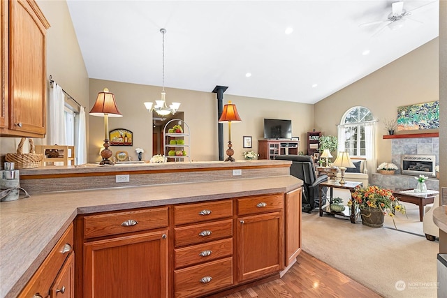 kitchen featuring lofted ceiling, decorative light fixtures, a fireplace, light wood-type flooring, and ceiling fan with notable chandelier