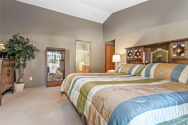 bedroom with light colored carpet, connected bathroom, and lofted ceiling