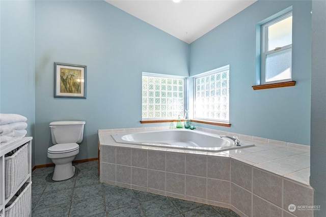 bathroom featuring a relaxing tiled tub, tile patterned floors, and toilet