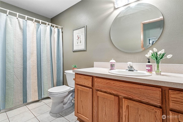 bathroom with toilet, vanity, and tile patterned flooring