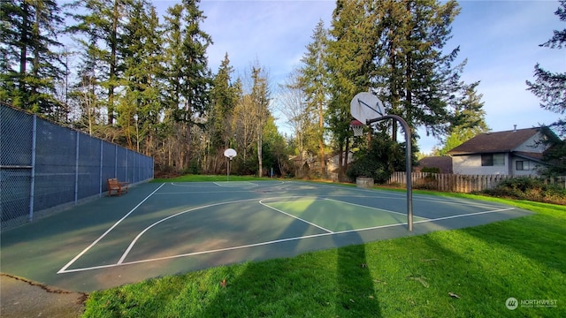 view of basketball court with community basketball court, fence, and a lawn