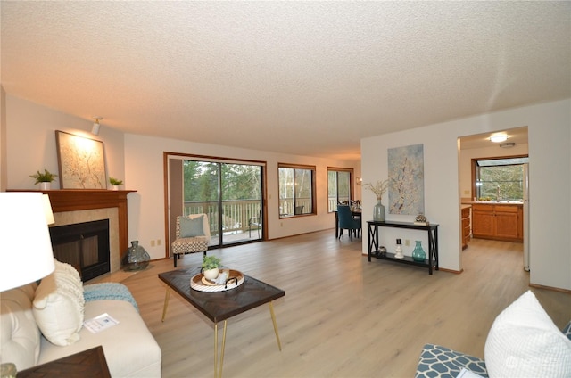 living room featuring light wood-style floors, plenty of natural light, and a tiled fireplace