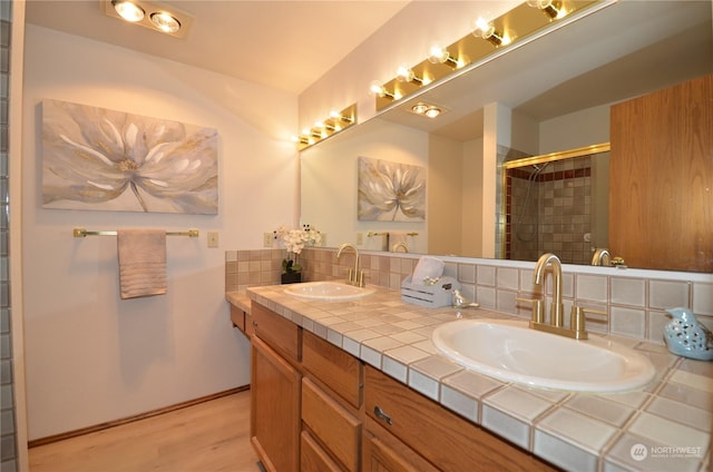 bathroom with double vanity, a tile shower, backsplash, and a sink