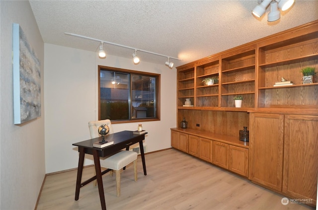 home office featuring light wood-style floors, baseboards, and a textured ceiling