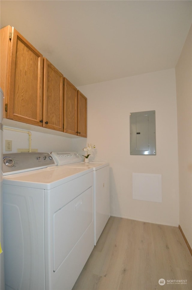 washroom featuring electric panel, cabinet space, light wood finished floors, and washer and clothes dryer