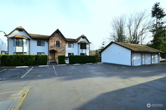 view of front of home featuring an outdoor structure, uncovered parking, and stone siding