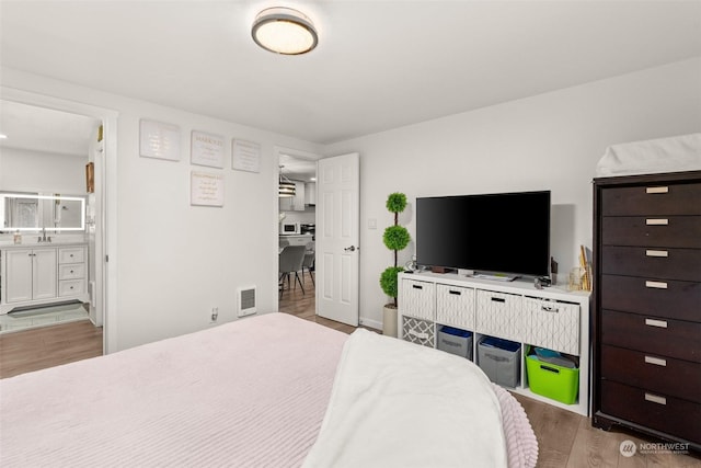 bedroom with sink, light hardwood / wood-style flooring, and ensuite bath