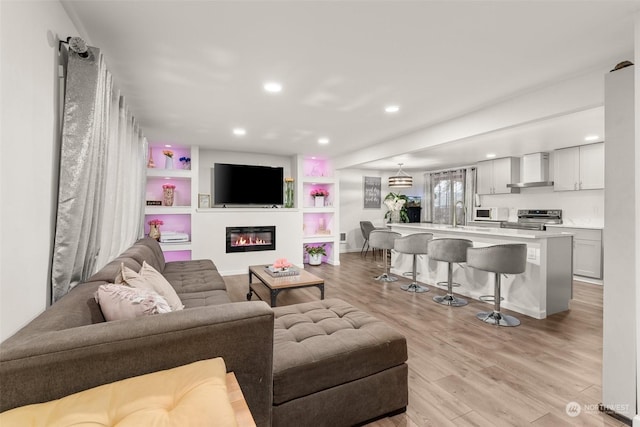 living room with sink, light hardwood / wood-style floors, and built in shelves