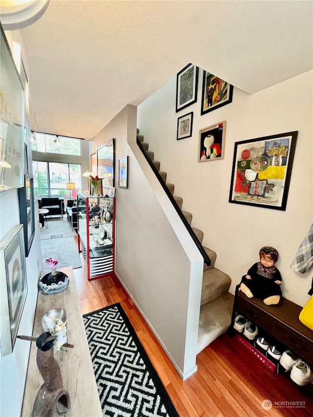 staircase featuring a textured ceiling and hardwood / wood-style floors