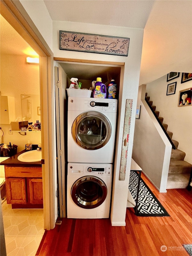 laundry room featuring sink, hardwood / wood-style floors, and stacked washer and dryer