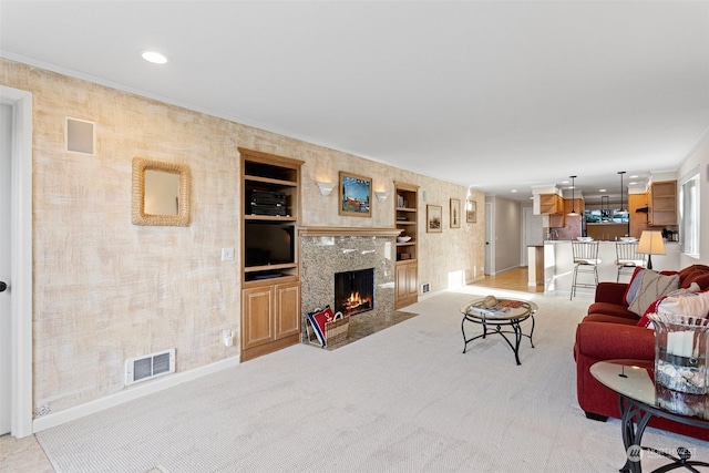 carpeted living room with crown molding, a high end fireplace, and built in features